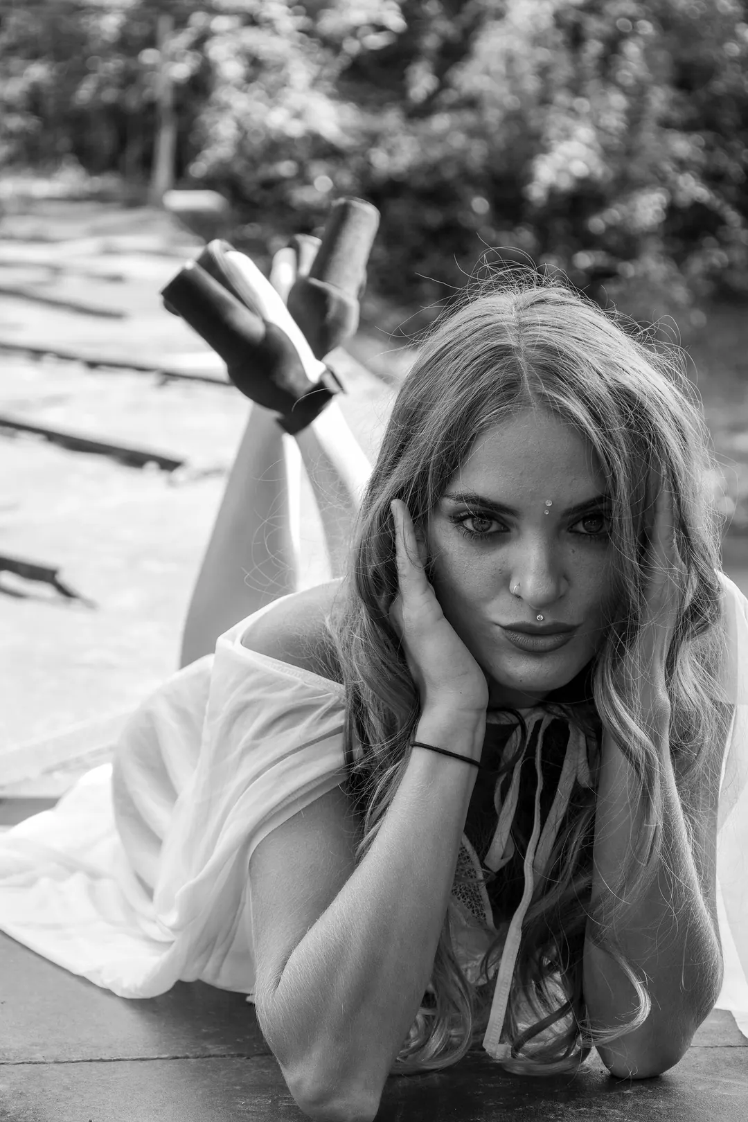 In bianco e nero, una ragazza sdraiata su un pontile con la mano tra i capelli.